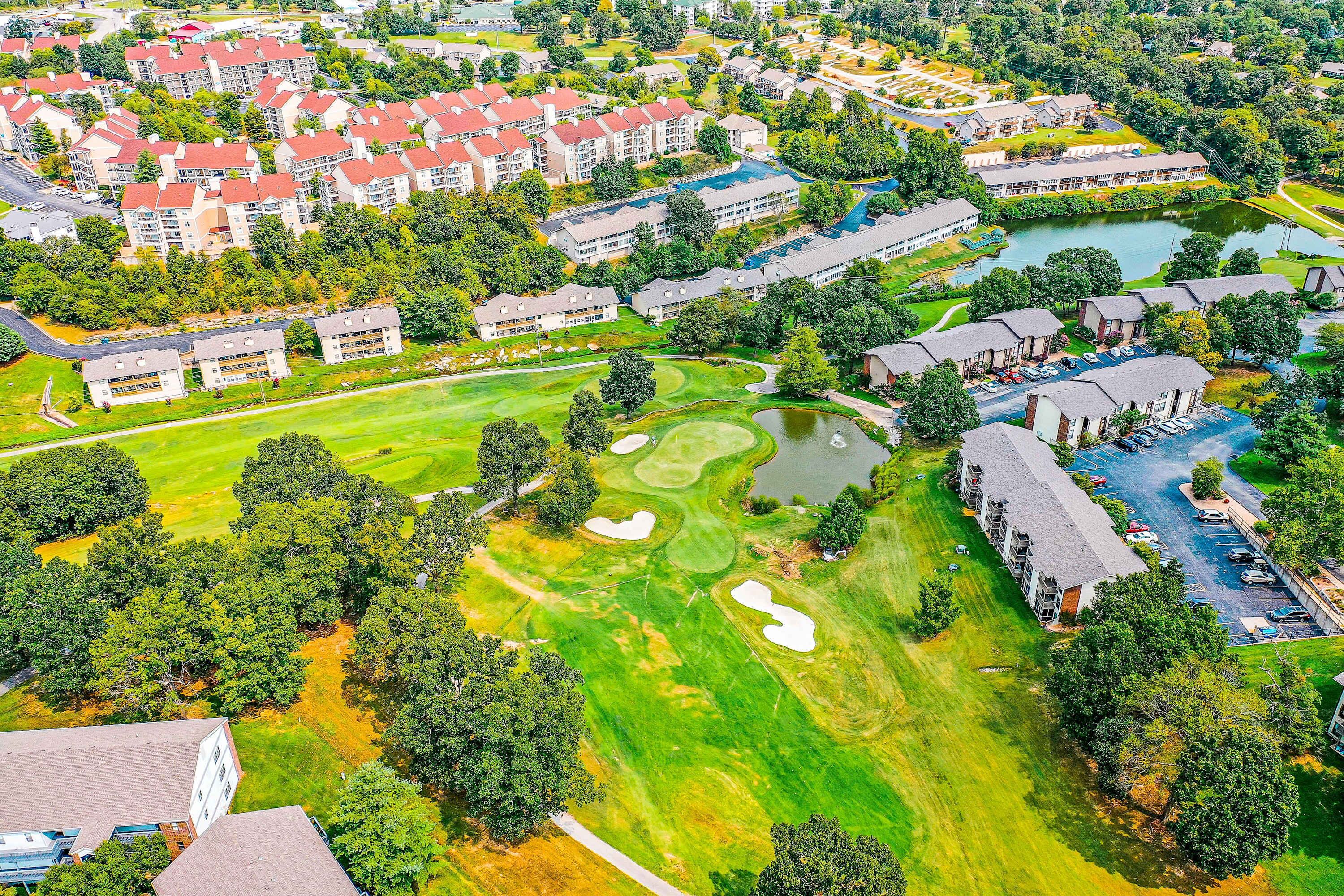 An aerial view of a residential area with apartment buildings, a golf course, and a body of water.
