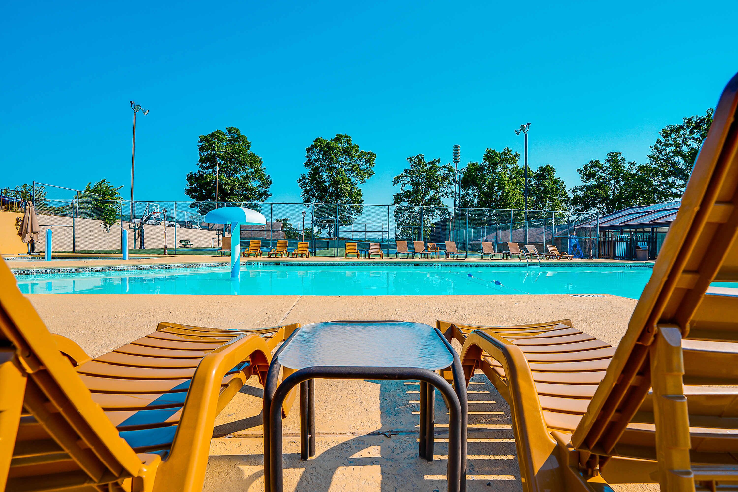 A pool area with lounge chairs and a clear blue sky.