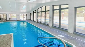 An indoor swimming pool with clear glass walls, a tiled floor, and a metal ladder. - Inviting 2BR Condo - HOT TUB - Family Pool (Branson)