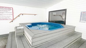 A spa with a hot tub, wooden steps, and a sign with health and safety rules. - Inviting 2BR Condo - HOT TUB - Family Pool (Branson)