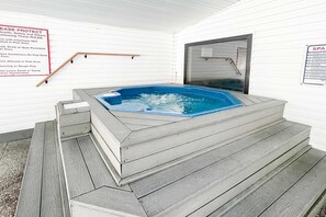 Ein Wellnessbereich mit Whirlpool, Holzstufen und einem Schild mit Gesundheits- und Sicherheitshinweisen.