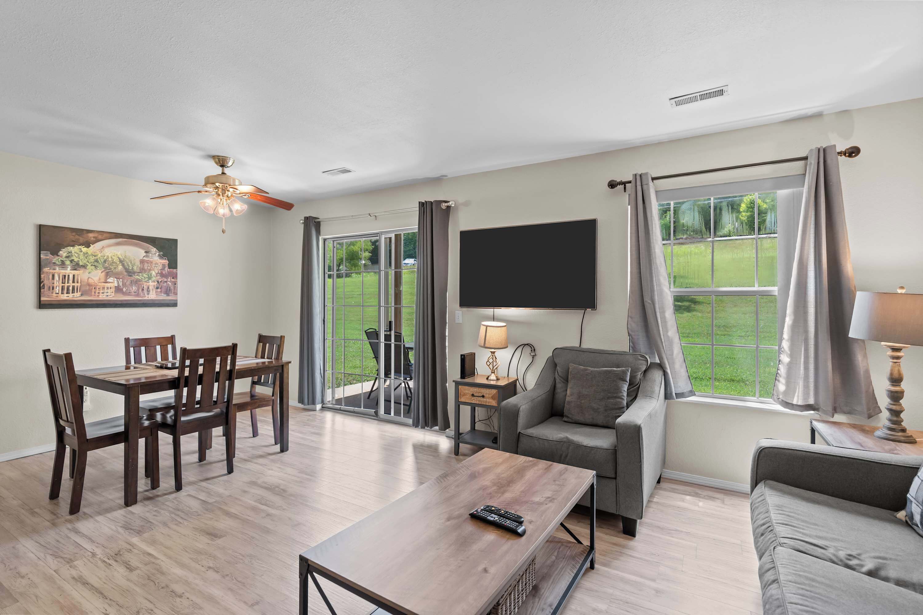 A living room with a dining table, chairs, a sofa, a TV, and a window with curtains.