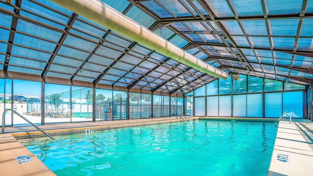 An indoor swimming pool with clear blue water, a metal roof, and a view of the outside. - Rustic 2BR Condo - POOL & GOLF - Pet Friendly (Branson)