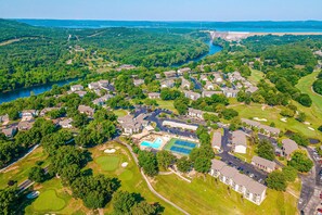 An aerial view of a residential area with houses, a swimming pool, tennis courts, and a golf course. - Rustic 2BR Condo - POOL & GOLF - Pet Friendly (Branson)
