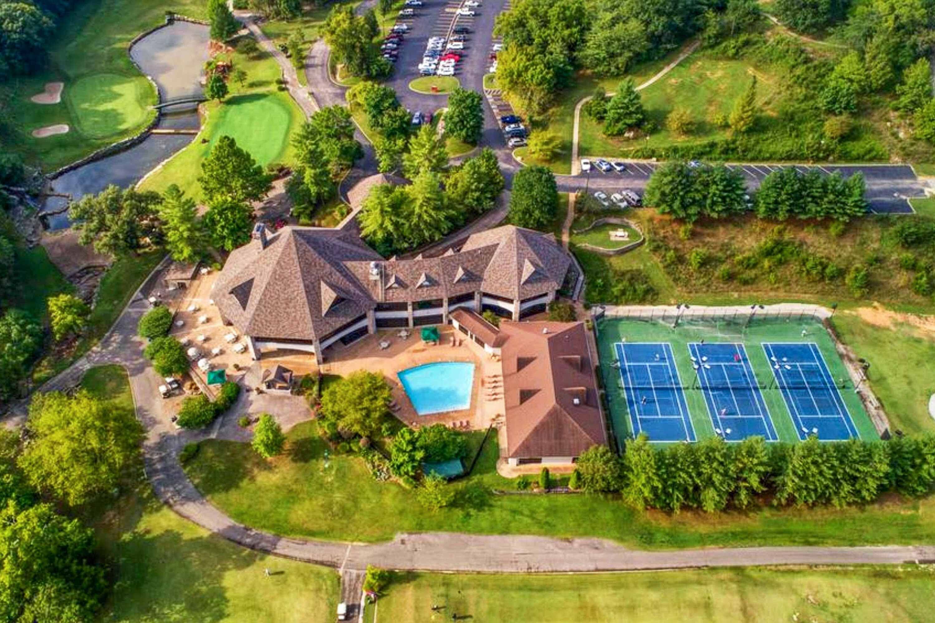 Ein großes, mehrstöckiges Gebäude mit Schwimmbad, Tennisplätzen und Golfplatz.