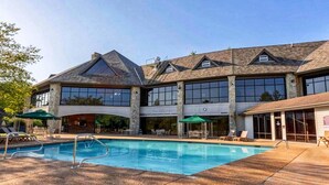 Un edificio con piscina, mobiliario exterior y amplias ventanas.