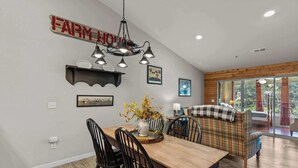 A dining area with a wooden table, black chairs, and a hanging light fixture. - Rustic 2BR Condo - FARMHOUSE STYLE - Fall Creek (Branson)