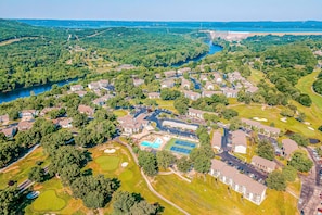 Vista aérea de una zona residencial con casas, piscina, canchas de tenis y un río.