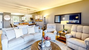A living room with a sofa, armchairs, a coffee table with decorative items, a lamp, and a painting on the wall. - Bright 2BR Condo - JETTED TUB & POOL - Branson (Branson)