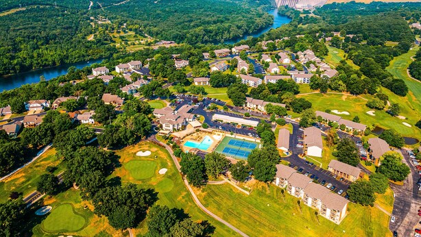An aerial view of a residential area with houses, a swimming pool, tennis courts, and a golf course. - Bright 2BR Condo - JETTED TUB & POOL - Branson (Branson)