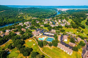 Vue aérienne d’un quartier résidentiel avec des maisons, une piscine, des courts de tennis et un terrain de golf.