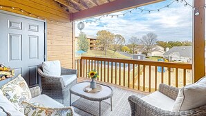 A covered outdoor area with wicker furniture, a door, and a view of a residential neighborhood. - Bright 2BR Condo - JETTED TUB & POOL - Branson (Branson)