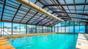 An indoor swimming pool with a glass ceiling, clear water, and a view of the outside. - Bright 2BR Condo - JETTED TUB & POOL - Branson (Branson)
