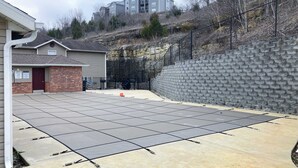 Ein gepflasterter Patio-Bereich mit einer Ziegelwand und einem Metallzaun.