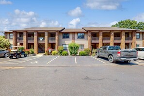 Ein mehrgeschossiges Motel mit Parkplatz, einem barrierefreien Stellplatz und einem kleinen Garten.