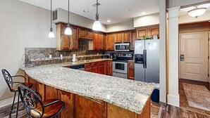 A kitchen with a large island, wooden cabinets, stainless steel appliances, and pendant lighting. - Bright 2BR Condo - Seasonal POOL - Branson (Branson)