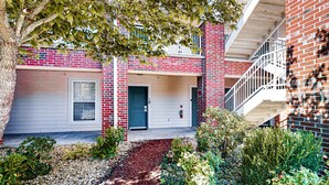 A two-story brick building with a front door, a small porch, and a staircase to an upper level. - Bright 2BR Condo - Seasonal POOL - Branson (Branson)