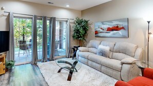 A living room with a sofa, a glass coffee table, and a painting on the wall. - Bright 2BR Condo - Seasonal POOL - Branson (Branson)