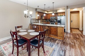 A kitchen with wooden cabinets, a granite countertop, and a dining area with a wooden table and chairs. - Bright 2BR Condo - Seasonal POOL - Branson (Branson)