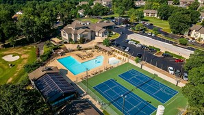 Vista aérea de uma área residencial com piscina, quadras de tênis e campo de golfe.