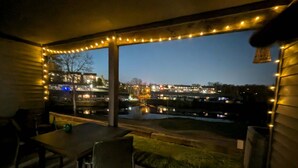 Uma área externa coberta com mesa e cadeiras, vista para a cidade e luzes de Natal.