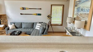 A living room with a gray sofa, a wooden coffee table, a bowl of fruit, and a painting on the wall. - Lakefront 4BR Cabin # POOL TABLE # Lake Views (Reeds Spring)