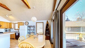 A kitchen with wooden cabinets, a dining table with chairs, a clock, and a hanging light fixture. - Lakefront 4BR Cabin # POOL TABLE # Lake Views (Reeds Spring)