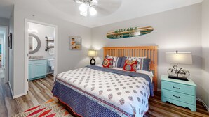 A bedroom with a bed, a nightstand, a ceiling fan, a bathroom with a toilet, and a door leading to another room. - Bright 3BR Condo - MOUNTAIN VIEWS - Community Pool (Branson)