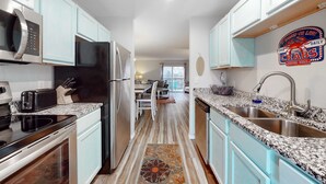 A kitchen with light blue cabinets, stainless steel appliances, granite countertops, and a patterned rug. - Bright 3BR Condo - MOUNTAIN VIEWS - Community Pool (Branson)