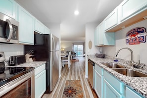 A kitchen with light blue cabinets, stainless steel appliances, granite countertops, and a patterned rug. - Bright 3BR Condo - MOUNTAIN VIEWS - Community Pool (Branson)