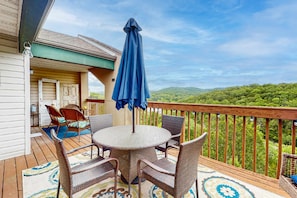 Une terrasse dotée de meubles en osier, d’une table ronde et d’un parasol bleu.