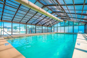 An indoor swimming pool with a glass ceiling, clear water, and a view of the outside. - Spacious 3BR Condo - JACUZZI TUB - Golf & Pools (Branson)