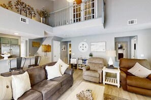 A spacious living area with a high ceiling, a staircase, and a kitchen in the background. - Spacious 3BR Condo - JACUZZI TUB - Golf & Pools (Branson)
