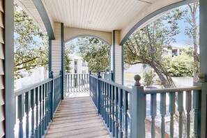 A covered wooden walkway with blue railings and a view of a white building in the distance. - Spacious 3BR Condo - JACUZZI TUB - Golf & Pools (Branson)