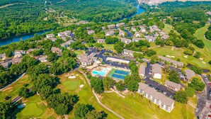 Vista aérea de uma área residencial com casas, piscina, quadras de tênis e campo de golfe.