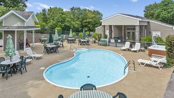 A swimming pool with lounge chairs, tables, and umbrellas.