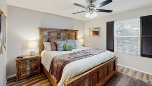 A bedroom with a bed, nightstands, a ceiling fan, a window with blinds, and a wooden headboard. - Serene 3BR Condo - MOUNTAIN VIEW - Community Pool (Branson)