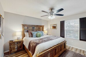 A bedroom with a bed, nightstands, a ceiling fan, a window with blinds, and a wooden headboard. - Serene 3BR Condo - MOUNTAIN VIEW - Community Pool (Branson)