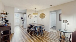 A modern kitchen with a dining table, bar stools, a chandelier, and a wall clock. - Serene 3BR Condo - MOUNTAIN VIEW - Community Pool (Branson)