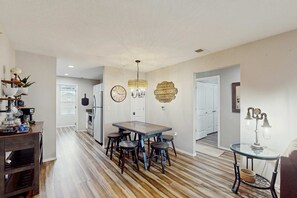 A modern kitchen with a dining table, bar stools, a chandelier, and a wall clock. - Serene 3BR Condo - MOUNTAIN VIEW - Community Pool (Branson)