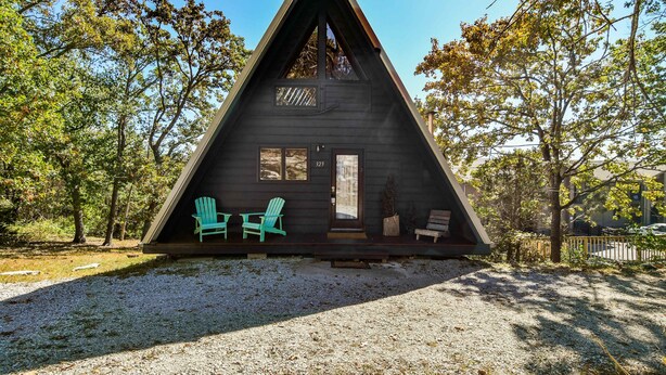 Een houten cabin met een terras, twee stoelen en een deur.