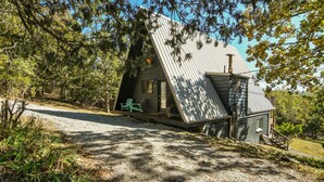 Een chalet met een schuin dak, een veranda en een grindpad.