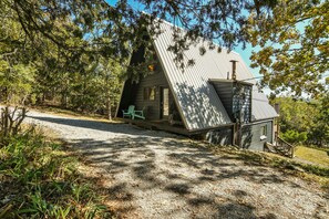 A cabin with a sloped roof, a porch, and a gravel driveway. - Woodsy 2BR A-Frame - HOT TUB - Pool Table & Lake (Indian Point)