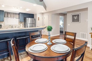 A dining area with a round table, chairs, and a central decorative piece. - Scenic 2BR Condo - OZARK VIEWS - Pool & Golf (Branson)