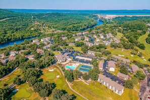 An aerial view of a residential area with houses, a swimming pool, tennis courts, and a golf course. - Scenic 2BR Condo - OZARK VIEWS - Pool & Golf (Branson)