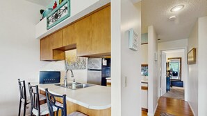 A modern kitchen with a bar area, wooden cabinets, and a stainless steel refrigerator. - Serene 1BR Retreat - GOLF VIEW - Pools & Fireplace (Branson)
