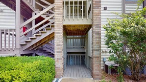A building with a wooden staircase, a covered entrance, and a small garden area. - Serene 1BR Retreat - GOLF VIEW - Pools & Fireplace (Branson)
