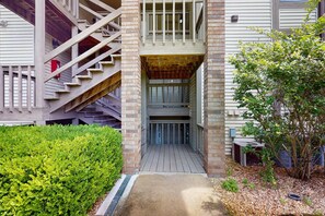 A building with a wooden staircase, a covered entrance, and a small garden area. - Serene 1BR Retreat - GOLF VIEW - Pools & Fireplace (Branson)