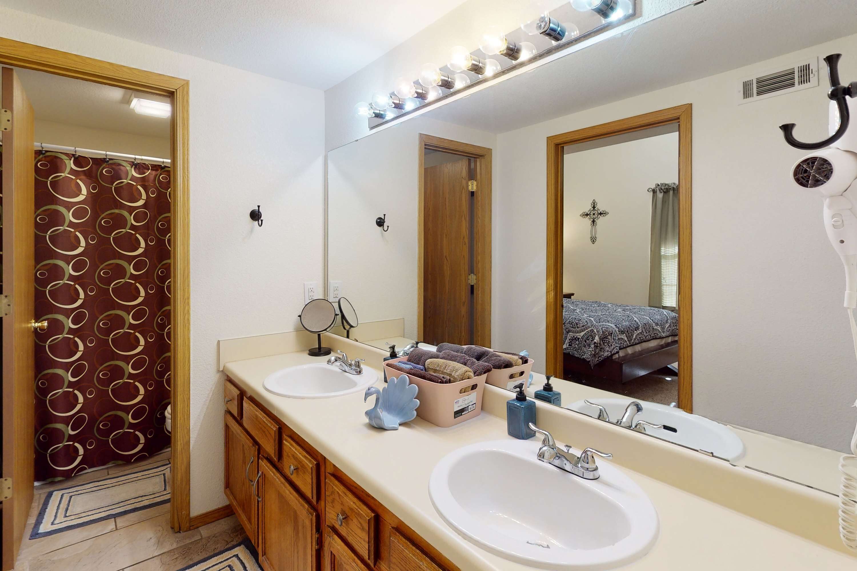 A bathroom with two sinks, a large mirror, and a shower area.