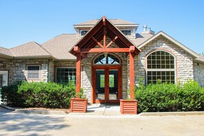 A stone building with a wooden porch, a large arched entrance, and a chimney. - Rustic 5BR Sanctuary - HOT TUB - Lake Access (Branson)